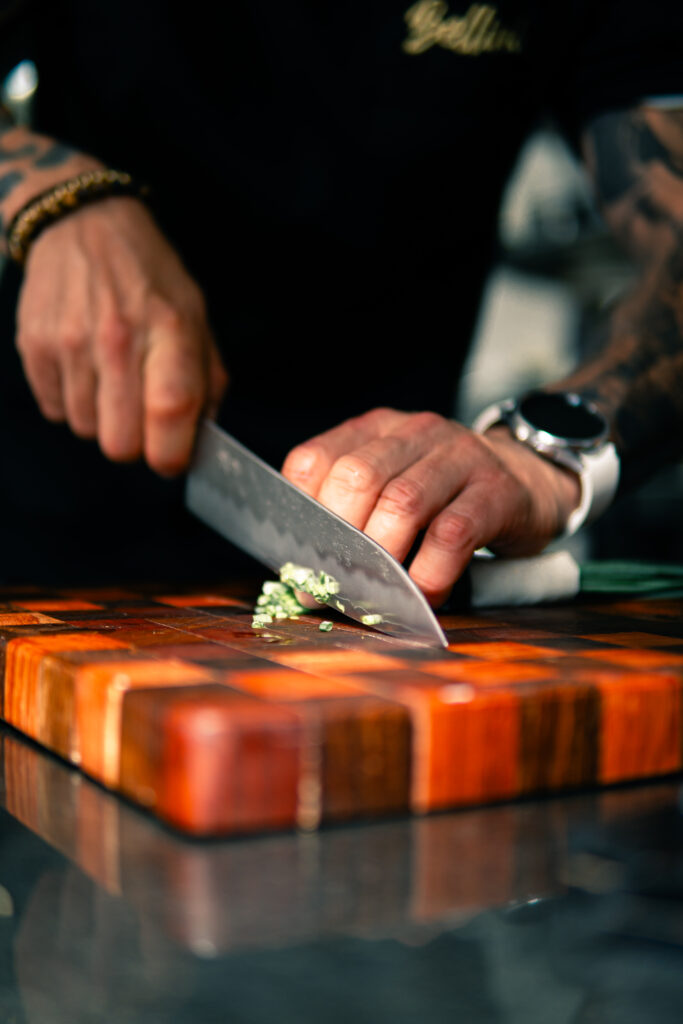 Chef slicing fresh herbs on a wooden board